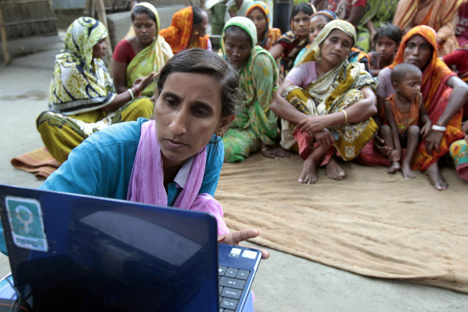 In this Sept. 30, 2012 photo, Sathi Akhtar, a 29-year-old Bangladeshi woman known as Tattahakallayani or Info Lady shows a 15-minute video played in a laptop at one of their usual weekly meetings at Saghata, a remote impoverished farming village in Gaibandha district, 120 miles (192 kilometers) north of capital Dhaka, Bangladesh. Dozens of “Info Ladies” bike into remote Bangladeshi villages with laptops and Internet connections, helping tens of thousands of people - especially women - get everything from government services to chats with distant loved ones. (AP Photo/A.M. Ahad)