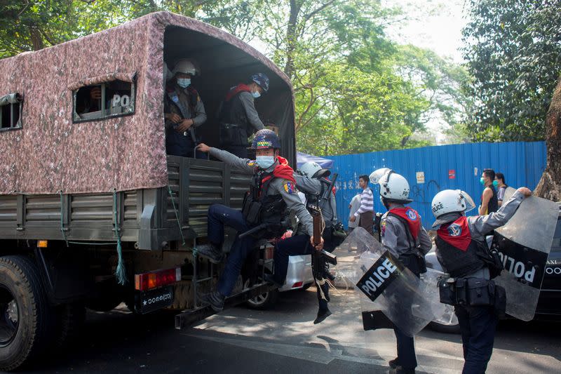 Riot police officers get on a police vehicle during a rally against the military coup, in Yangon