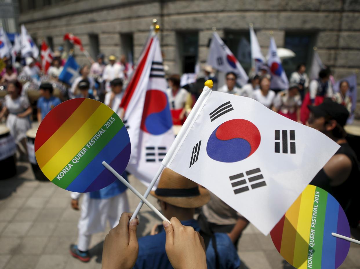 A participant in the Seoul, South Korea pride festival holds up the rainbow pride flag (left) and the South Korean flag (right).