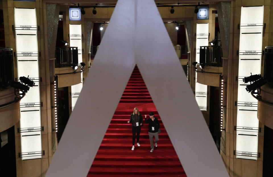 People walk along the red carpet during preparations for Sunday's red carpet arrivals at the 92nd Academy Awards at the Dolby Theatre, Saturday, Feb. 8, 2020, in Los Angeles. (AP Photo/John Locher)