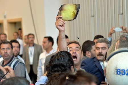 An unidentified political party representative holds up a paper claiming that it is a burnt ballot, at the vote counting and collection center for the parliamentary election in Ankara, Turkey, June 7, 2015. REUTERS/Stringer