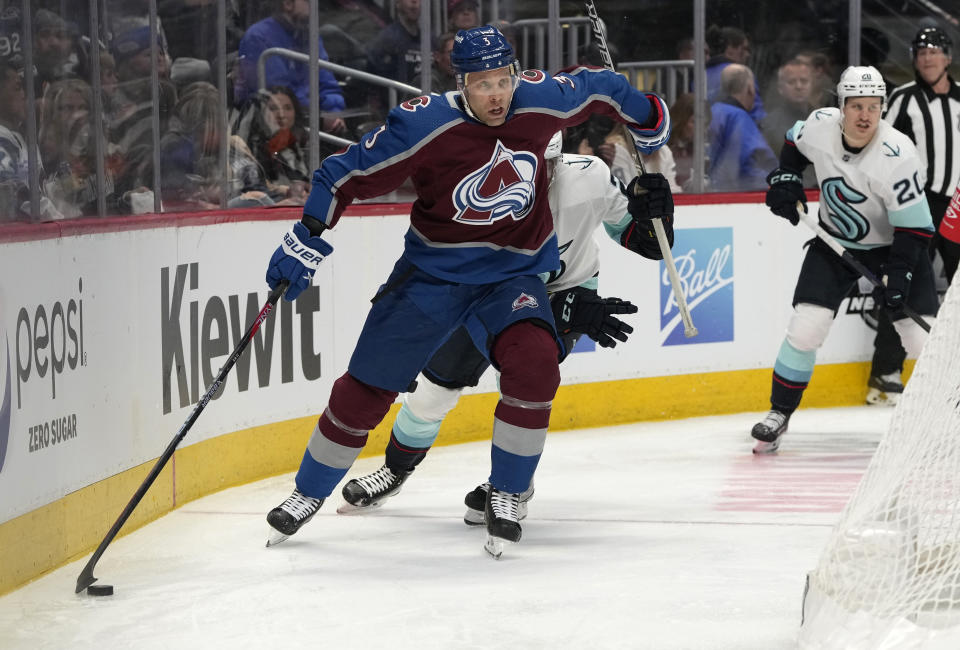 Colorado Avalanche defenseman Jack Johnson, front, collects the puck while fending off Seattle Kraken center Alex Wennberg in the second period of an NHL hockey game, Sunday, March 5, 2023, in Denver. (AP Photo/David Zalubowski)