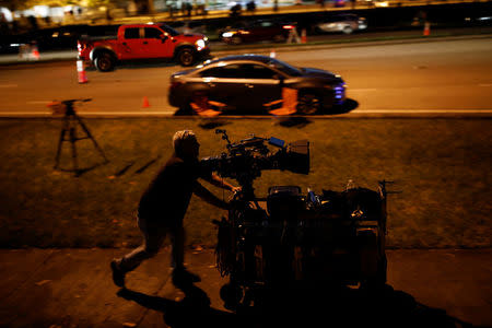 A member of the media pushes a cart full of equipment in front of Marjory Stoneman Douglas High School, following a mass shooting in Parkland, Florida, U.S., February 18, 2018. REUTERS/Carlos Garcia Rawlins