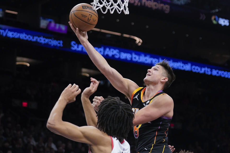 Phoenix Suns' Grayson Allen (8) puts a layup past Portland Trail Blazers' Shaedon Sharpe during the first half of an NBA basketball game in Phoenix, Monday, Jan. 1, 2024. (AP Photo/Darryl Webb)