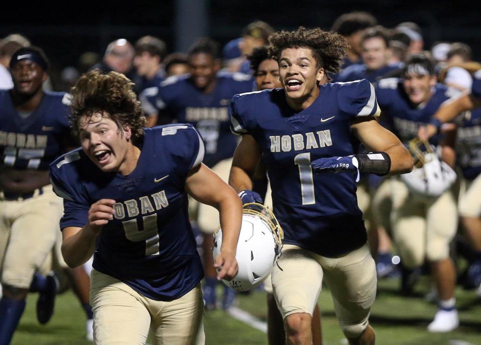 Hoban's Charlie Durkin, left, and Tyson Grimm, right, celebrate with teammates after earning a 35-34 win over Walsh Jesuit on Friday, Sept. 3, 2021, in Akron, Ohio. [Jeff Lange/Beacon Journal]