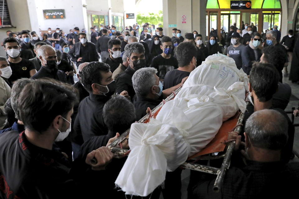 Mourners carry the body of a person who died from COVID-19, at the Behesht-e-Zahra cemetery just outside Tehran, Iran, Wednesday, April 21, 2021. After facing criticism for downplaying the virus last year, Iranian authorities have put partial lockdowns and other measures in place to try and slow the coronavirus’ spread. (AP Photo/Ebrahim Noroozi)