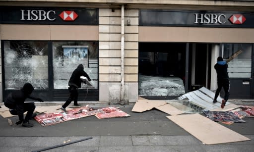 Demonstrators in Paris, some masked and hooded, broke shop windows along their route and threw projectiles at police in riot gear, who responded with tear gas