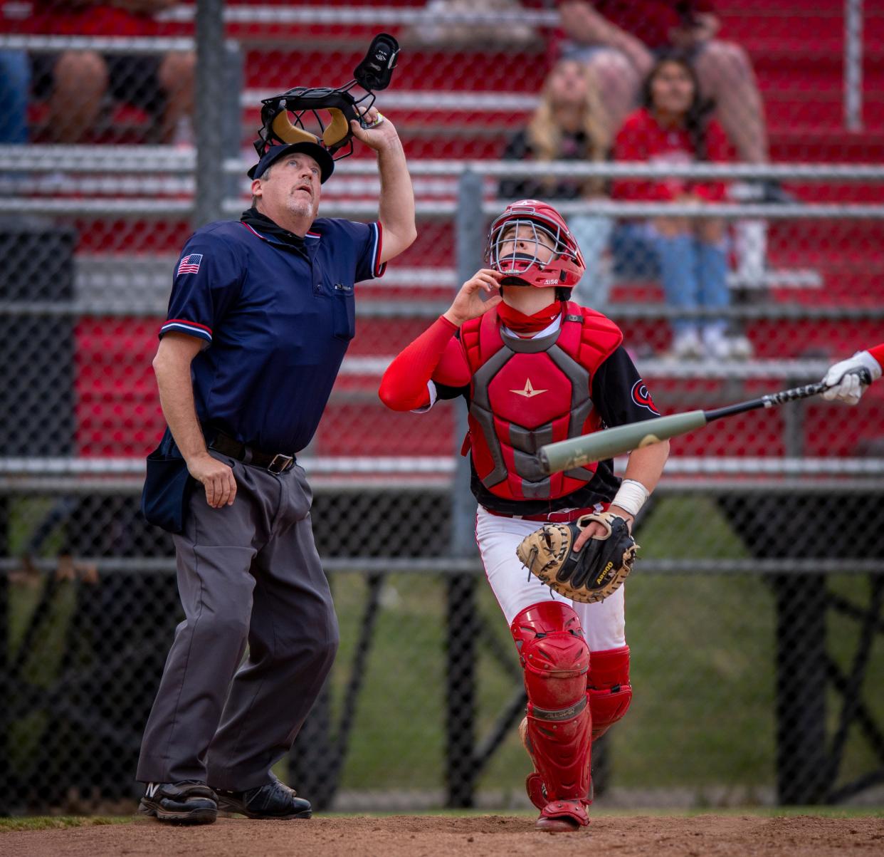 Umpire Greg Wright takes his mask off to better spot a fly ball in foul territory during a Roncalli at Center Grove high school game. Because of COVID-19 and other factors, an umpire shortage is causing cancelations this spring season.