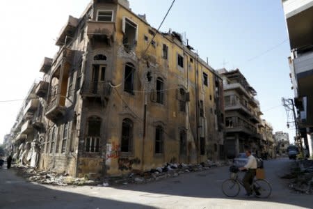 FILE PHOTO: A man rides a bicycle near a building damaged during the Syrian conflict between government forces and rebels in Homs, Syria May 13, 2014. REUTERS/Omar Sanadiki