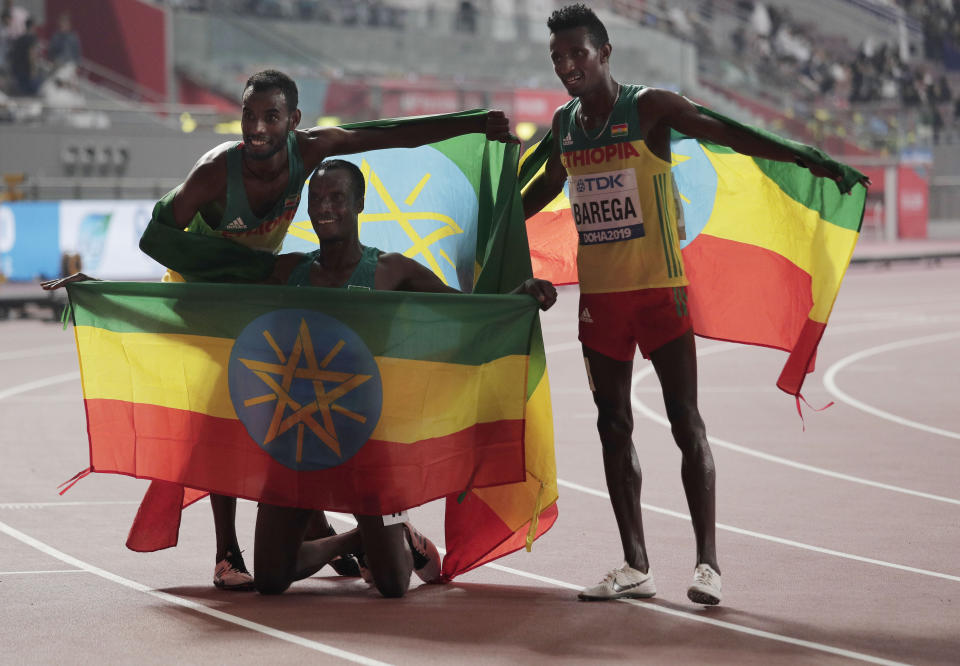 Muktar Edris, of Ethiopia, gold, center, Selemon Barega, of Ethiopia, silver, right, and fourth placed Telahun Haile Bekele, of Ethiopia, pose with their national flag after the men's 5000 meter final at the World Athletics Championships in Doha, Qatar, Monday, Sept. 30, 2019. (AP Photo/Nariman El-Mofty)