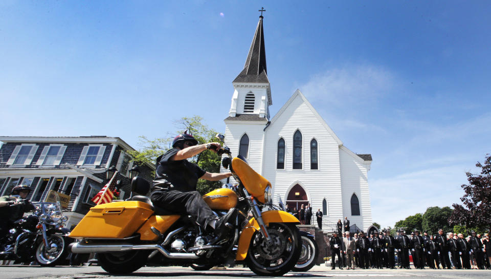 Members of the Jarheads Motorcycle Club pass police honor guards as they roll up to the funeral for Michael Ferazzi at St. Peter's Catholic Church in Plymouth, Mass., Friday, June 28, 2019. Ferazzi, a motorcyclist and retired police officer, was killed in a fiery crash that claimed the lives of seven people riding with the Jarheads Motorcycle Club in New Hampshire. (AP Photo/Charles Krupa)