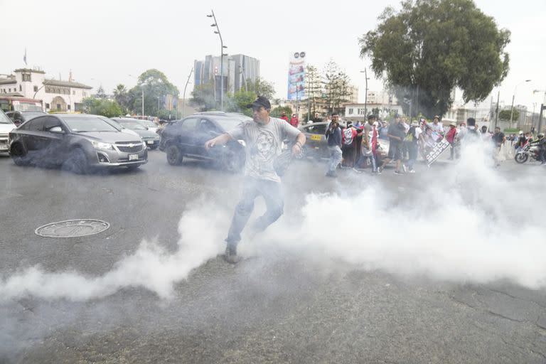 Un manifestante arroja de vuelta un gas lacrimógeno a la policía en Lima, en vísperas de la "toma" de la ciudad