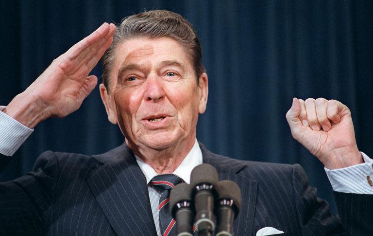 Late US president Ronald Reagan salutes as he tells a joke during his address to the leadership of the American Legion, February 1987 at the White House in Washington, DC