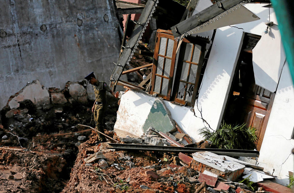 A police officer inspects a damaged house