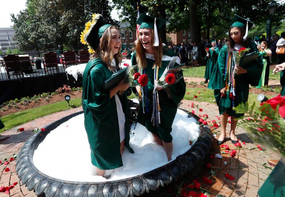 Graduates Madison Tucker, left, and Julia Pemberton get into the fountain to celebrate after the William Peace University commencement on the university’s main lawn in Raleigh.