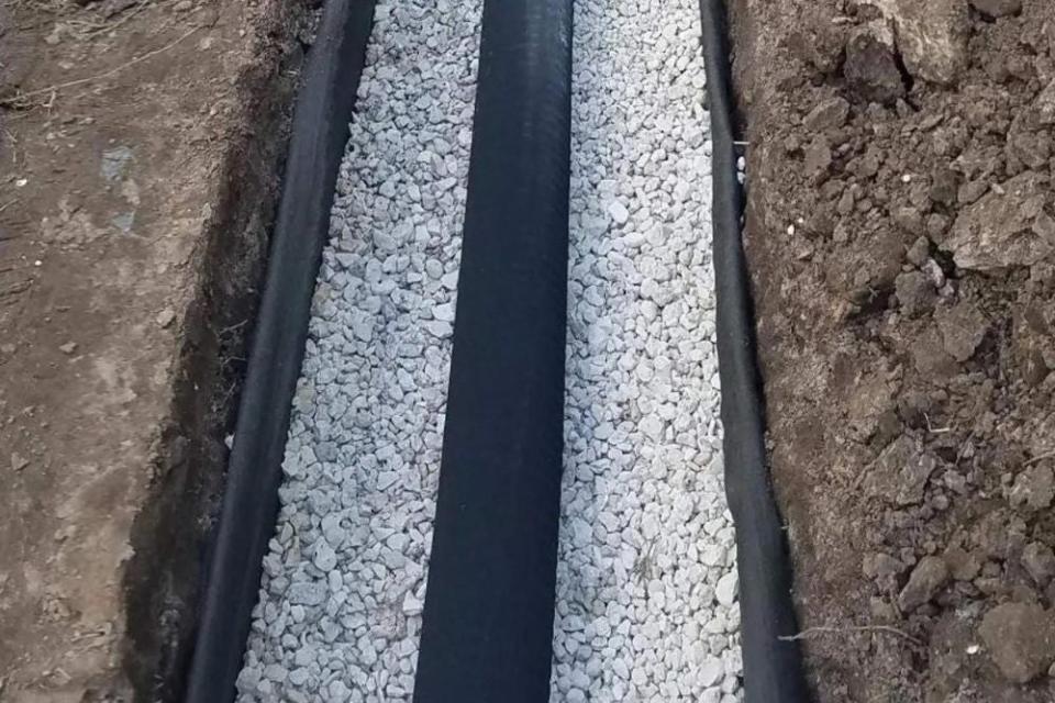 A close up of two parallel french drains filled with rocks. 