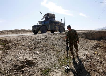 An Afghan National Army (ANA) soldier searches for mines during a patrol while a Humvee is seen in the background in Logar province, Afghanistan February 16, 2016. REUTERS/Omar Sobhani