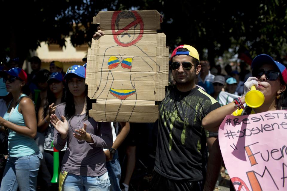 Un hombre sostiene un cartón con una caricatura del presidente venezolano Nicolás Maduro en un bikini, durante una manifestación antigubernamental en Valencia, Venezuela, el sábado 1 de marzo de 2014. (Foto AP/Rodrigo Abd)