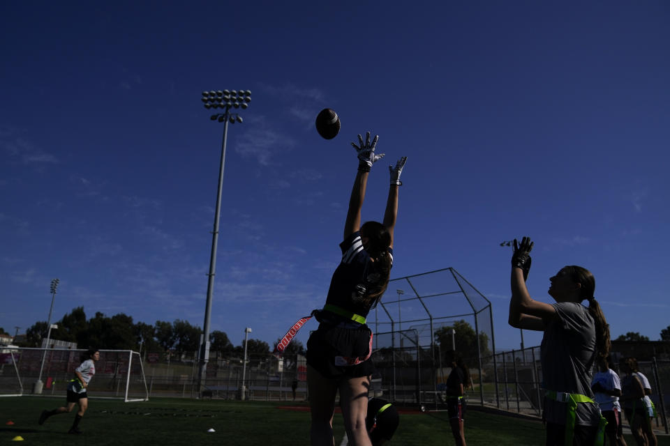 Aly Young, center, reaches to catch a pass as she and other Redondo Union High School girls try out for a flag football team on Thursday, Sept. 1, 2022, in Redondo Beach, Calif. Southern California high school sports officials will meet on Thursday, Sept. 29, to consider making girls flag football an official high school sport. This comes amid growth in the sport at the collegiate level and a push by the NFL to increase interest. (AP Photo/Ashley Landis)