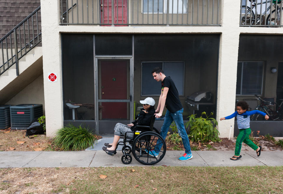 Jan Miguel pushes his mother, Mariluz, in a wheelchair on their way to get a ride to a doctor appointment. Jan Miguel&rsquo;s cousin Emiliano follows closely. (Photo: Chris McGonigal/HuffPost)