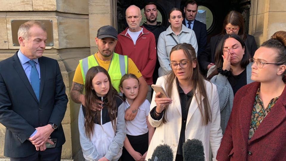 Tia Skelton, centre, the sister of Lewis Skelton, is surrounded by members of their family and solicitor Neil Hudgell, left, as she reads a statement to the media outside Hull Coroner’s Court (Dave Higgens/PA) (PA Wire)