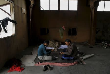 Afghan immigrants play cards inside a wood factory across the street from a ferry terminal in the western Greek town of Patras April 28, 2015. REUTERS/Yannis Behrakis