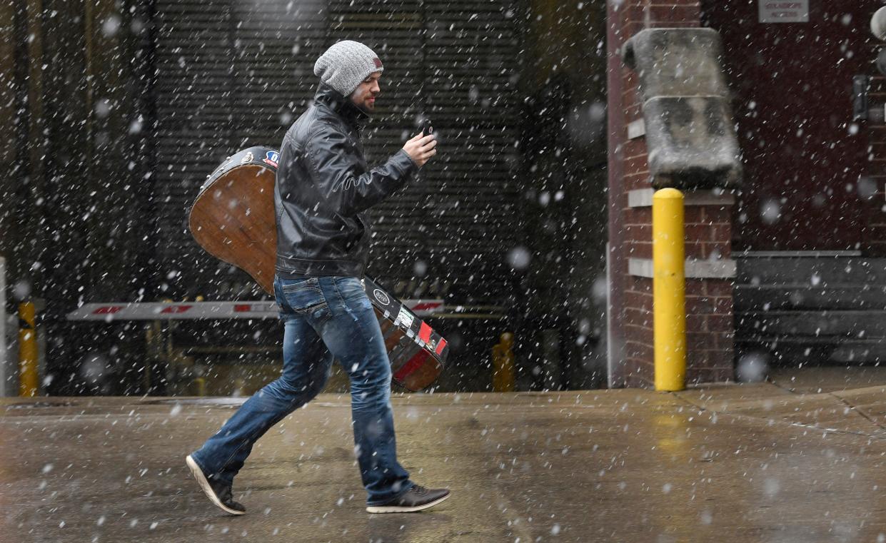 A musician does a FaceTime chat as he walks to show the snow that just arrived as he carries his guitar back to his car Friday Jan. 12, 2018, in Nashville, Tenn