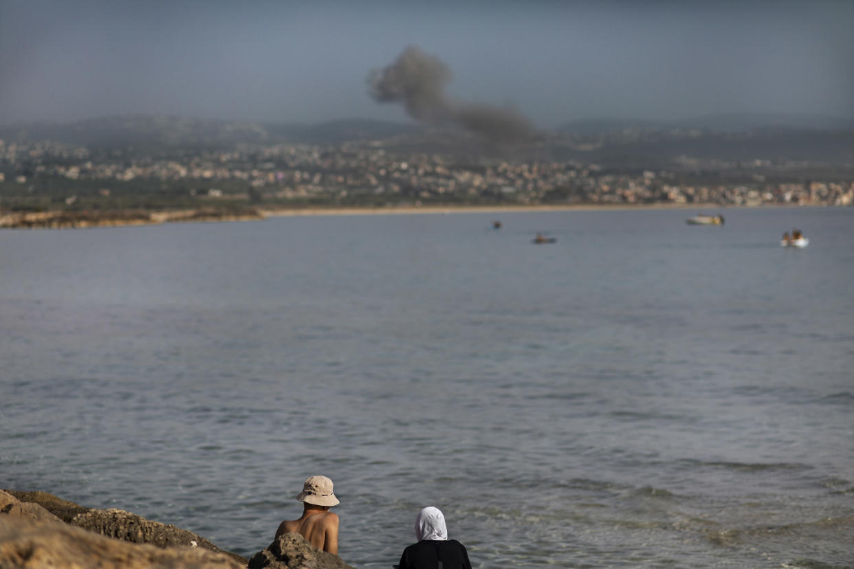 A couple watch smoke rise after an Israeli airstrike, in Tyre, Lebanon, May 20, 2024. (Diego Ibarra Sanchez/The New York Times)