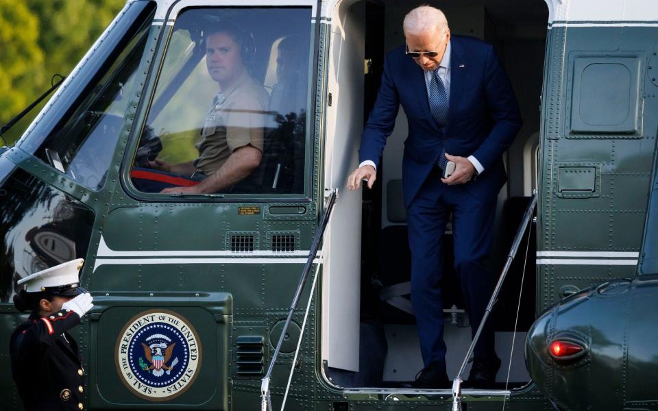 Joe Biden, pictured exiting Marine One, is claimed to be using a team of 'walkers' to disguise his shuffling gait