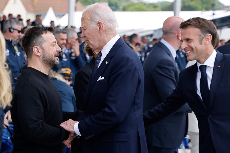 El presidente de Estados Unidos, Joe Biden, saluda al mandatario de Ucrania, Volodimir Zelensky, junto a su par francés, Emmanuel Macron, durante las celebraciones en homenaje a los 80 años del Día D