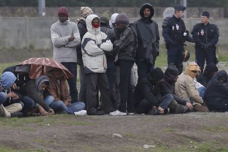 French riot police stand guard as migrants wait during daily food distribution in Calais October 24, 2014. REUTERS/Pascal Rossignol