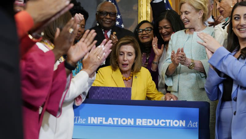 House Speaker Nancy Pelosi, D-California, surrounded by House Democrats, signs the Inflation Reduction Act of 2022 during a bill enrollment ceremony on Capitol Hill in Washington, Friday, Aug. 12, 2022. What has the bill accomplished in the year since it’s been passed?