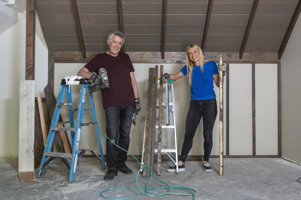 Barry Williams (Greg) and host Jasmine Roth pose after installing old wood planks, salvaged from the basement, to recreate the decor of Greg's attic in the original Brady House. (Photo: Gilles Mingasson/Getty Images)