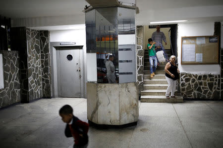 Residents walk down stairs carrying a container to collect water, at an apartment block in downtown Caracas, Venezuela, March 19, 2019. REUTERS/Carlos Garcia Rawlins