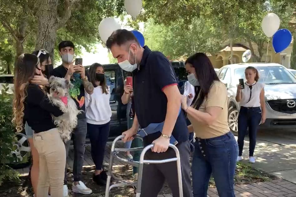 Hernando Rodríguez walks with the help of a walker and his wife, Solangi Urueña, behind him, as he is discharged from the hospital after 78 days in Doral, Fla., on April 8. (Juliana Jiménez J. / Telemundo News)