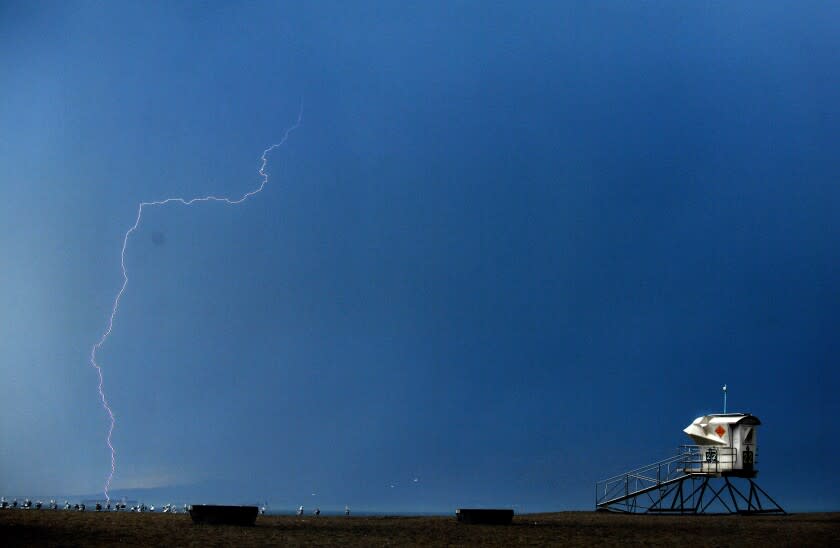 A lightning bolt strikes the ocean near a lifeguard tower at Bolsa Chica State Beach as a storm passes through on Monday.