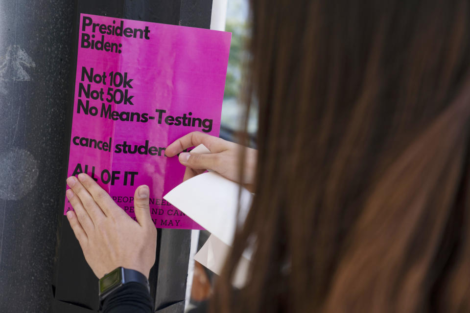 American University student Magnolia Mead puts up posters near the White House promoting student loan debt forgiveness,  / Credit: Evan Vucci / AP