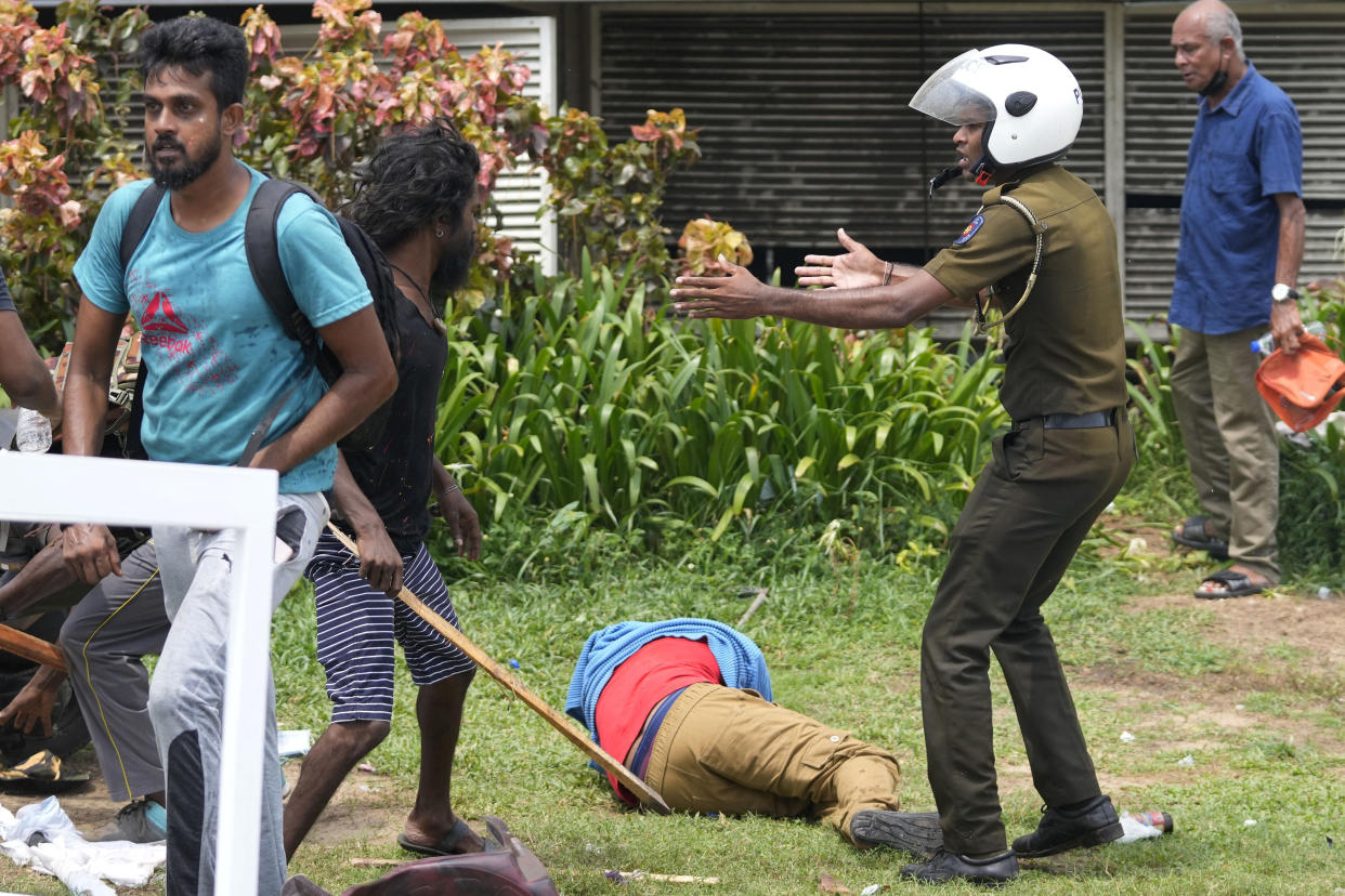 A Sri Lankan policeman prevents an anti-government protester, second left, from attacking a government supporter lying on the ground during clashes outside president's office in Colombo, Sri Lanka, Monday, May 9, 2022. Authorities deployed armed troops in the capital Colombo on Monday hours after government supporters attacked protesters who have been camped outside the offices of the country's president and prime minster, as trade unions began a “Week of Protests” demanding the government change and its president to step down over the country’s worst economic crisis in memory. (AP Photo/Eranga Jayawardena)