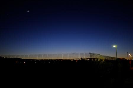 The moon is seen over the border fence between Morocco and Spain's north African enclave Melilla December 5, 2013. REUTERS/Juan Medina