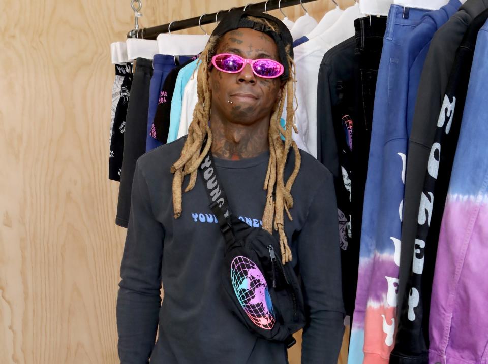 Wayne doesn't smile while posing for a photo wearing a backwards hat and pink sunglasses