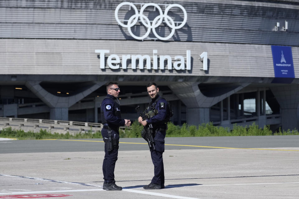 Gendarmes stand in from of the Charles de Gaulle airport, terminal 1, where the olympic rings were installed, is seen in Roissy-en-France, north of Paris, Tuesday, April 23, 2024 in Paris. (AP Photo/Thibault Camus)