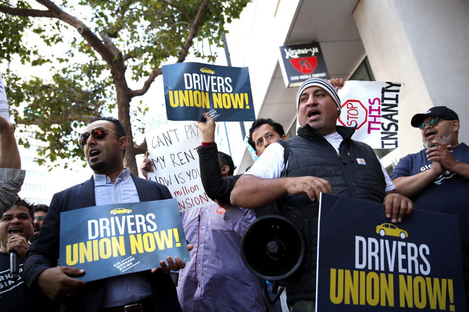 SAN FRANCISCO, CALIFORNIA - AUGUST 27: Rideshare drivers wave flags and hold signs during a protest outside of Uber headquarters on August 27, 2019 in San Francisco, California. Dozens of Uber and Lyft drivers staged a protest outside of Uber headquarters in support of California assembly bill 5 and to organize a union for rideshare drivers. (Photo by Justin Sullivan/Getty Images)