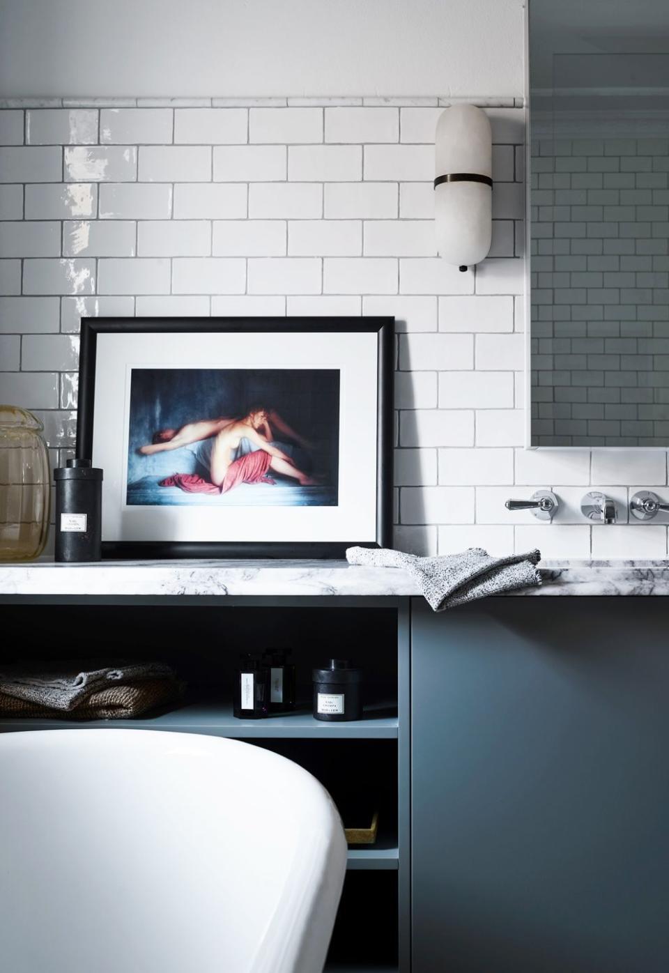 <p>Rather than hanging fine art on the walls, simply lean it on the counter for an effortlessly cool elegance, as done in this moody bathroom designed by Arent & Pyke. </p>