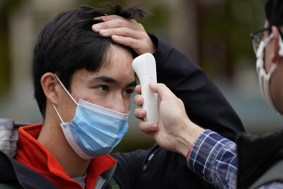 Will Surks, of Westfield, N.J., a freshman at Bowdoin College, has his temperature checked as a safety measure to help prevent the spread of the coronavirus, before being allowed into a campaign event for Sara Gideon, Democratic candidate for U.S. Senate, at the Town Mall, Thursday, Oct. 29, 2020, in Brunswick, Maine. Gideon, the speaker of the Maine House, is challenging incumbent Republican Sen. Susan Collins. (AP Photo/Robert F. Bukaty)