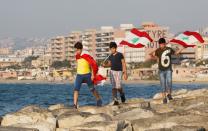 Youths carry Lebanese flags during an anti-government protest in the southern city of Nabatiyeh, Lebanon