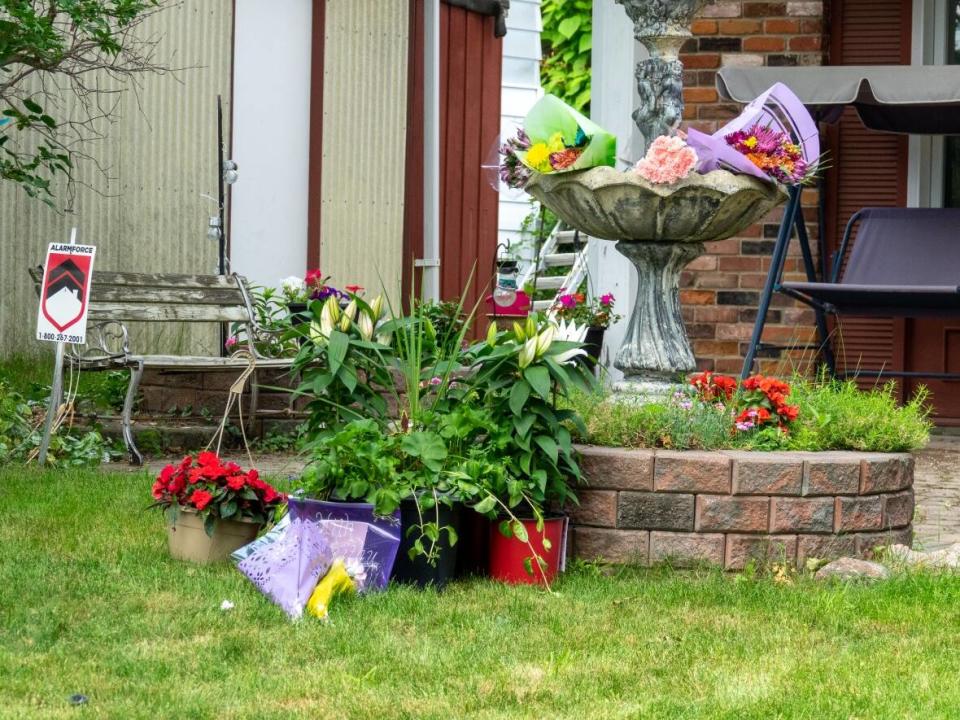 Bunches of flowers are seen on the Ready family's front lawn on Anoka Street in south Ottawa's Alta Vista neighbourhood on Thursday. Anne-Marie Ready, 50, and her daughter Jasmine Ready, 15, were stabbed to death at late Monday night. Catherine Ready, 19, survived. (Francis Ferland/CBC - image credit)