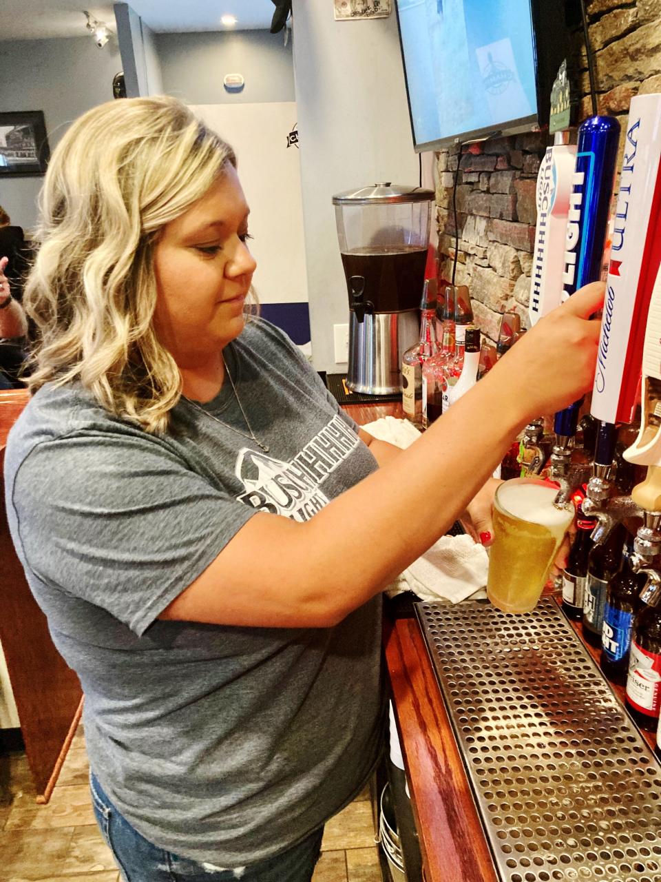 Bartender Alyssa Busby pours beer at Champs Pizza and Pub in Thornport. Champs, owned by Brad and Erin Turnes, is one of many bars and restaurants that have made adjustments to their menus as inflation affects bottom lines throughout the industry.