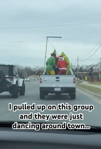 Santa Claus, the Grinch, and a person in a yellow costume dance in the back of a moving pickup truck. Text: "I pulled up on this group and they were just dancing around town..."