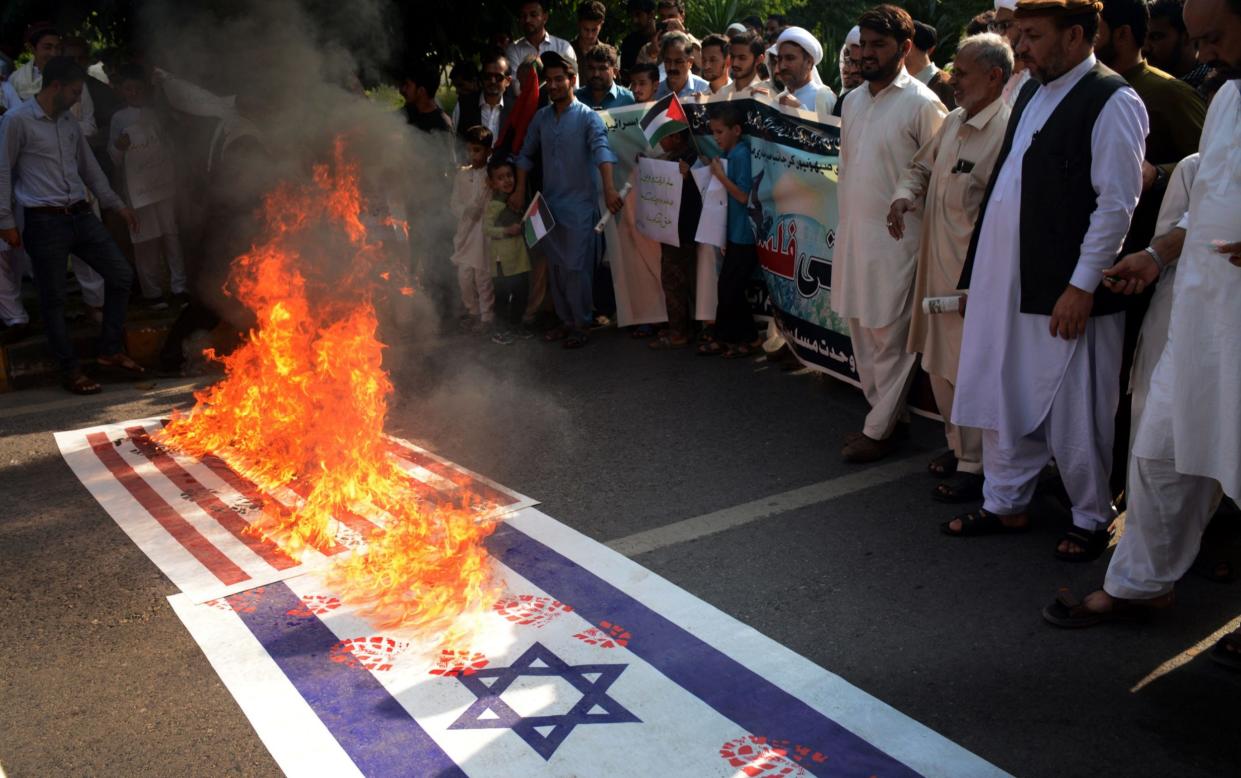 People burn a US and Israeli flag during a demonstration in solidarity with the Palestinian people