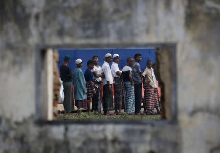 Rohingya migrants who arrived in Indonesia last week by boat are seen through the window of an abandoned building as they wait in line for breakfast at a temporary shelter in Aceh Timur regency near Langsa in Indonesia's Aceh Province May 27, 2015. REUTERS/Darren Whiteside